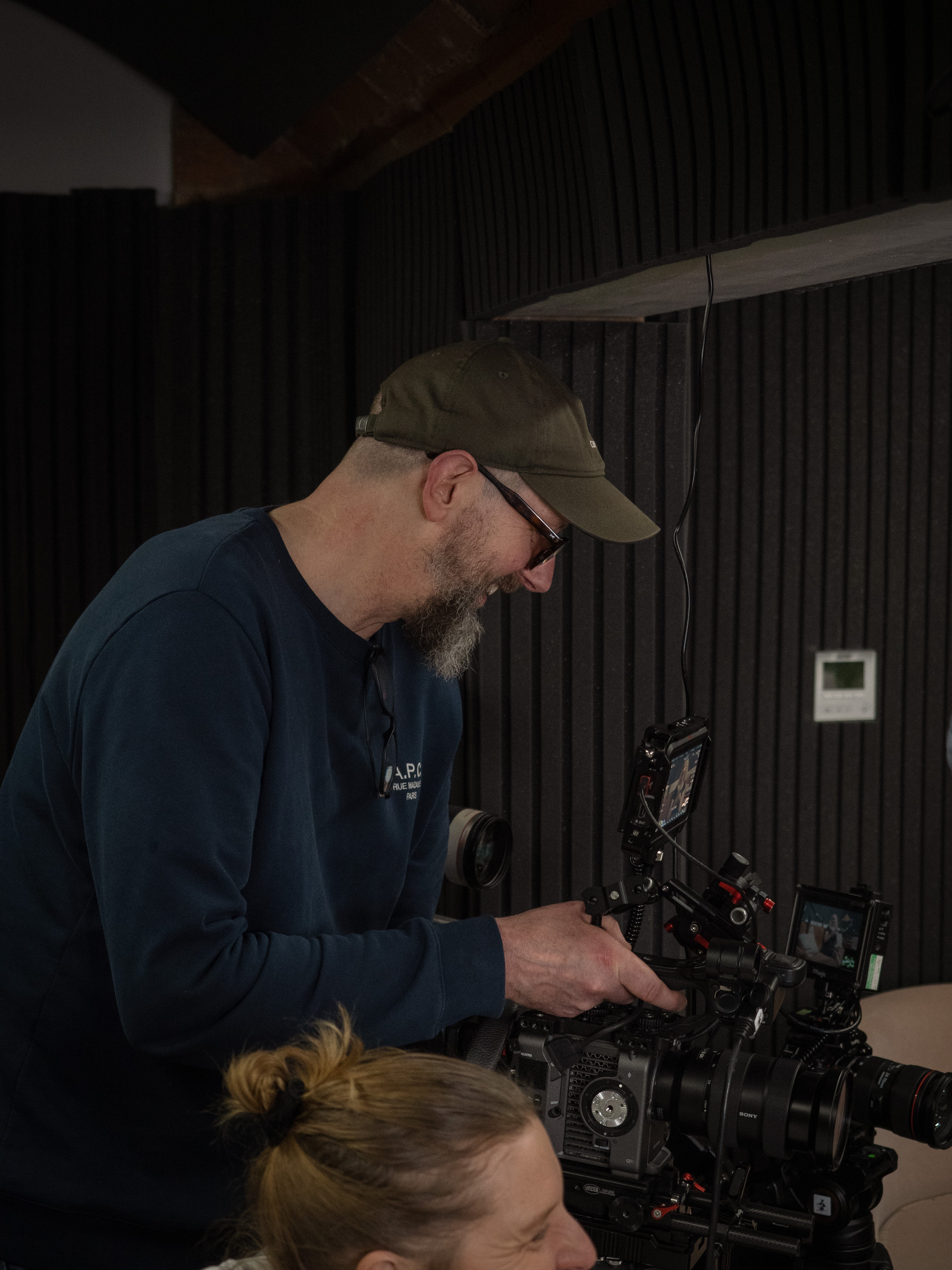 Person operating video camera equipment with a dark background