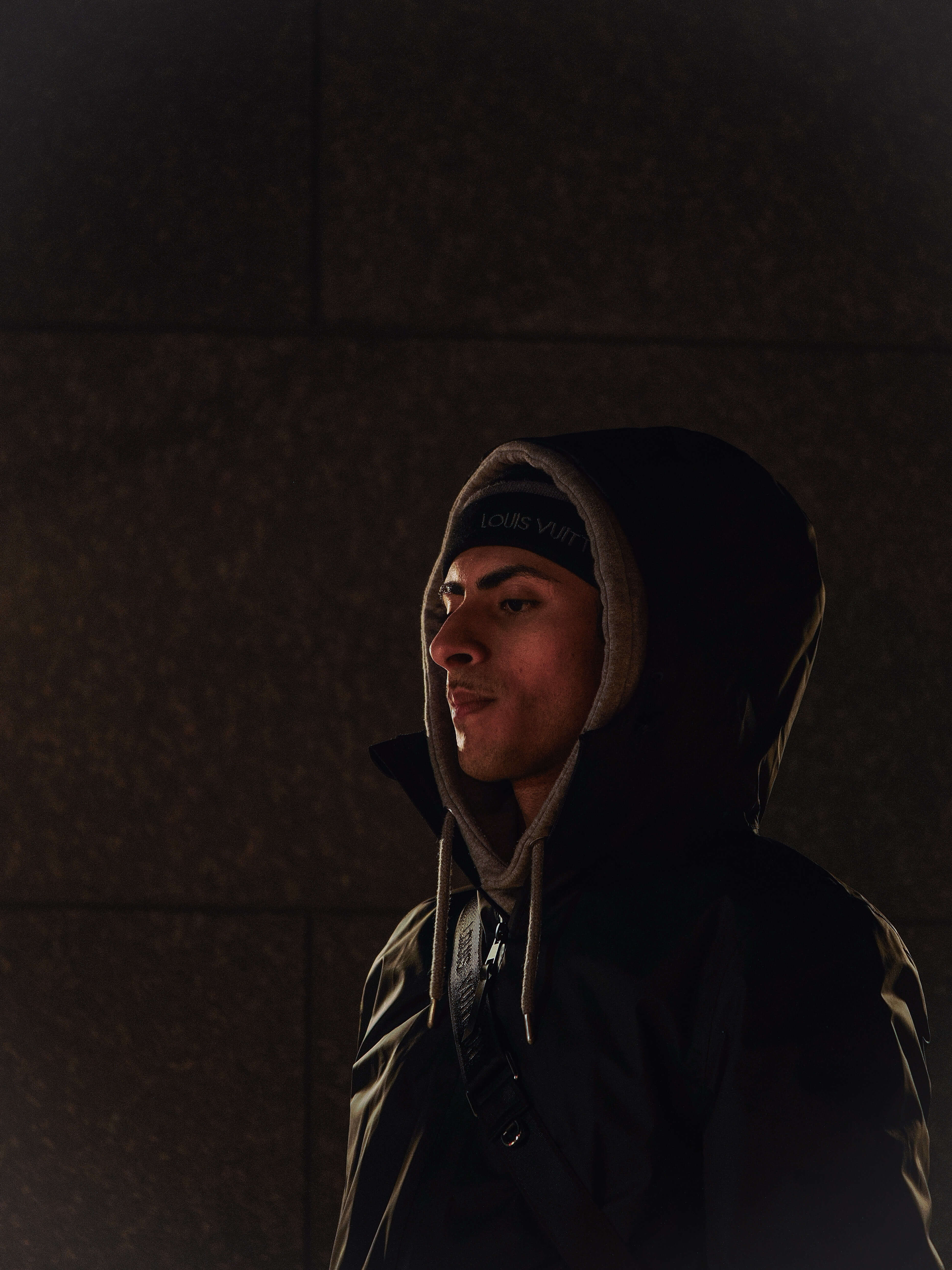 Model wearing a hooded jacket in a dark street setting
