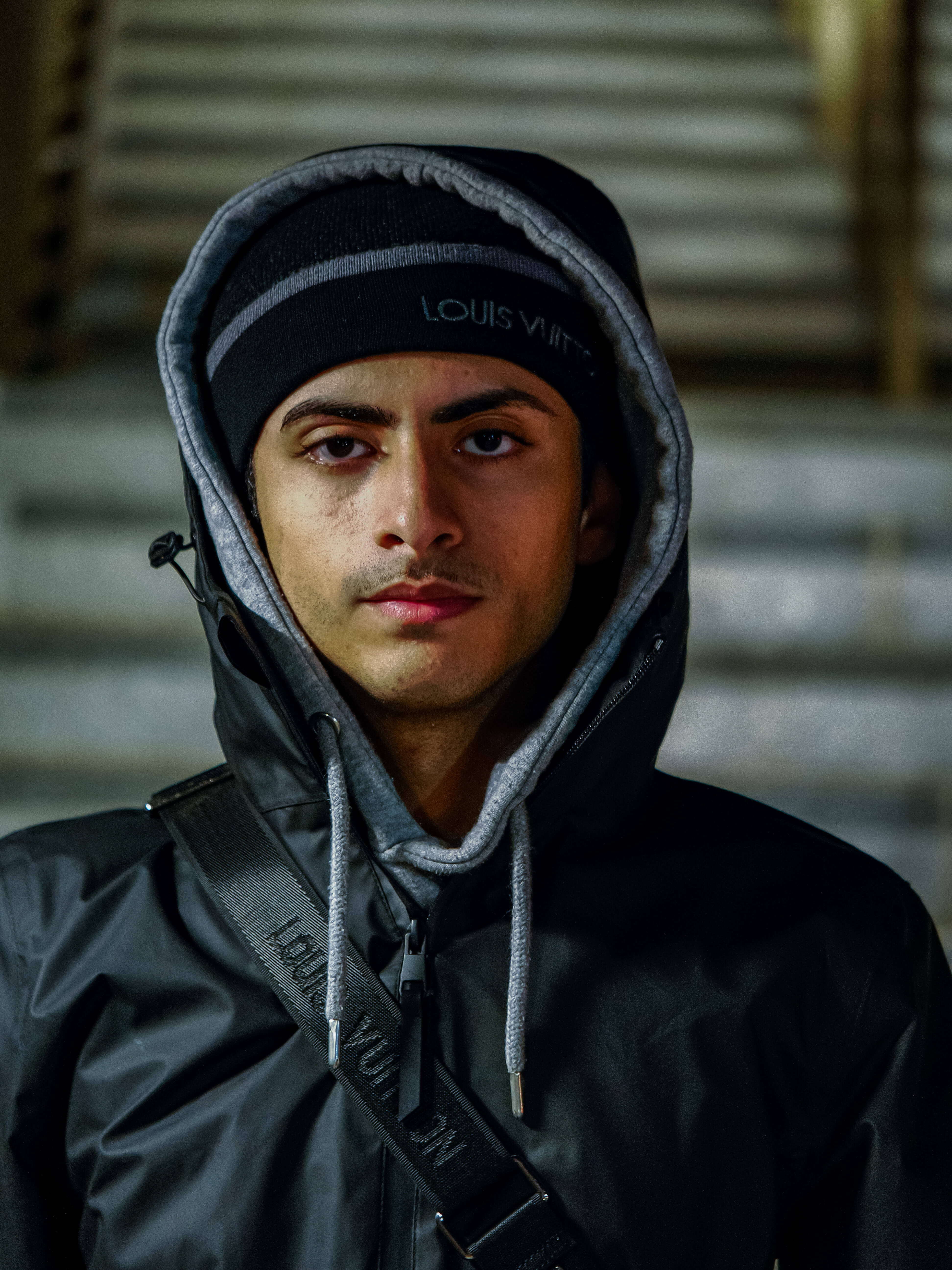 Male Model wearing a black Louis Vuitton jacket with a hood in an urban setting