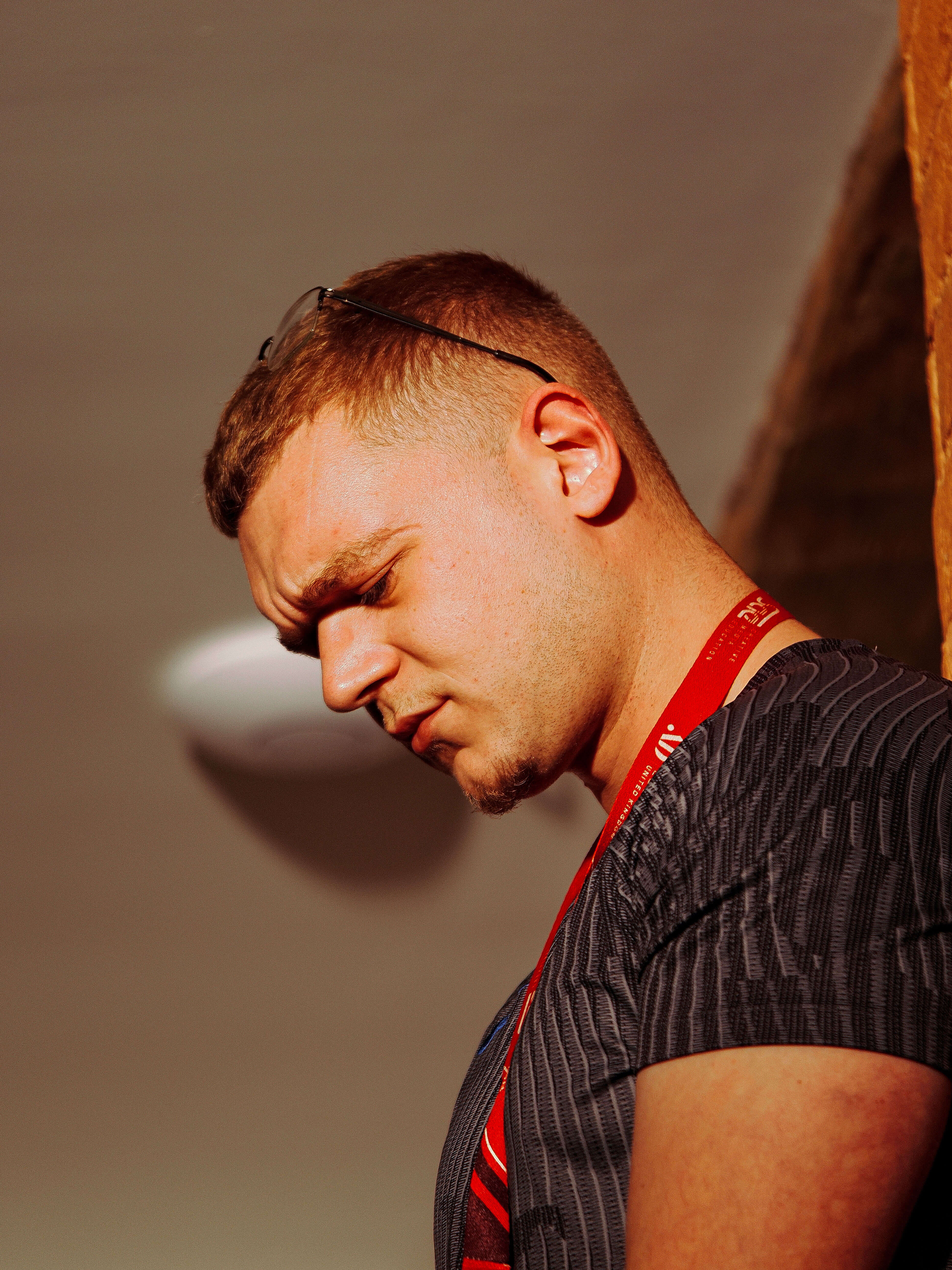 Portrait of a man wearing a red lanyard and dark top against a neutral background