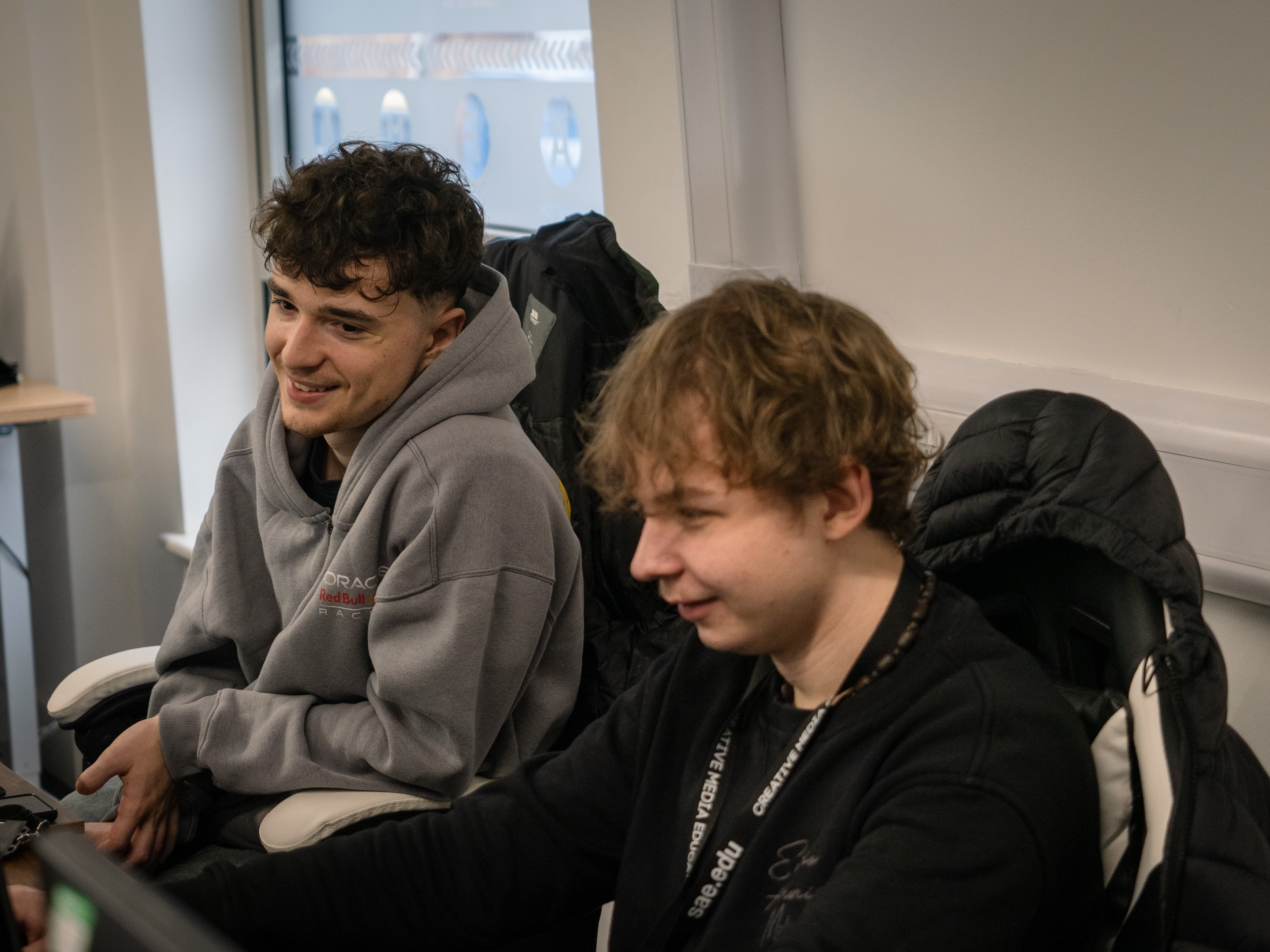 Two individuals sitting together in a casual setting with backpacks around.