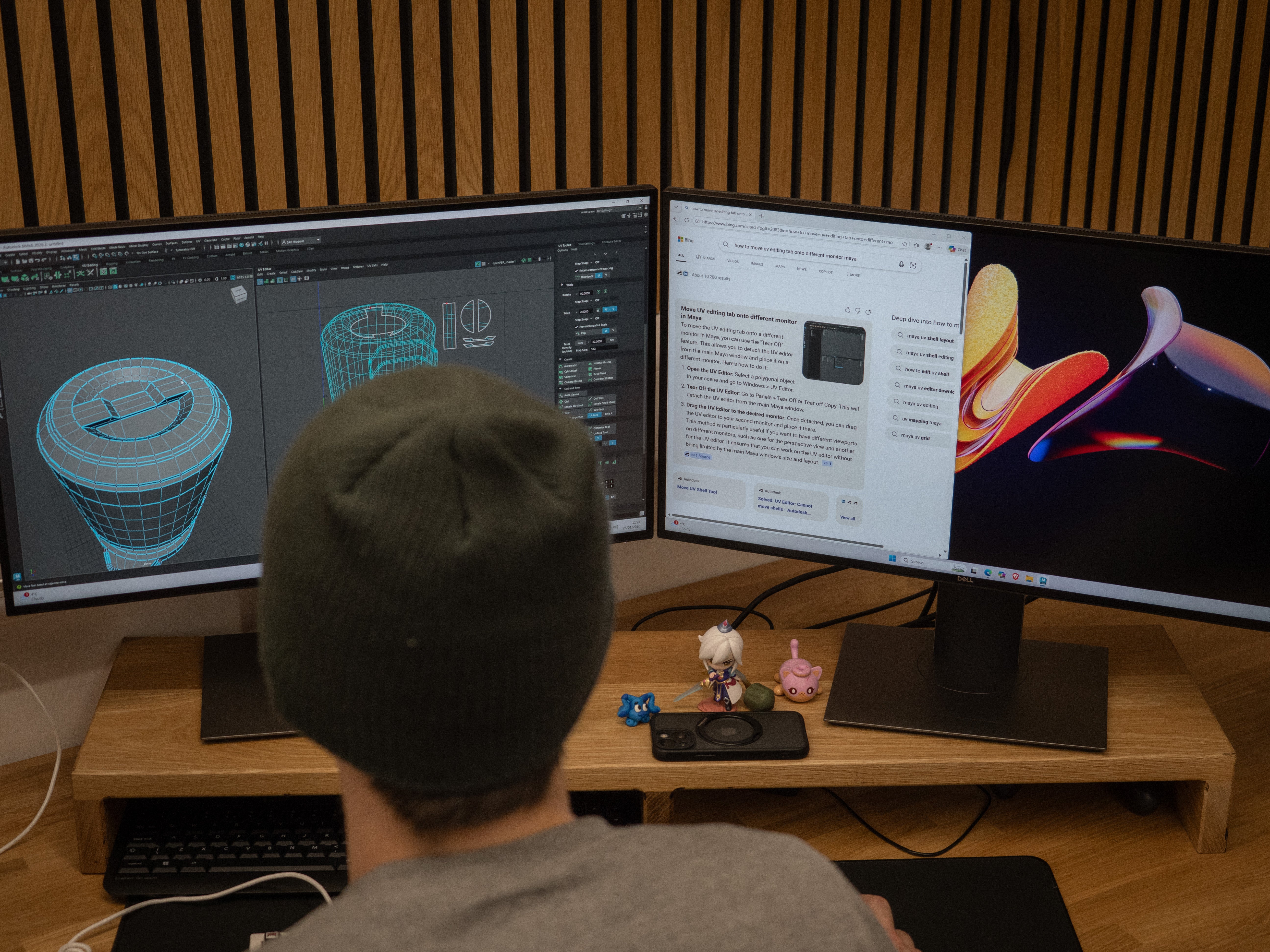 Person working at a desk with multiple computer monitors displaying 3D models and software interfaces.