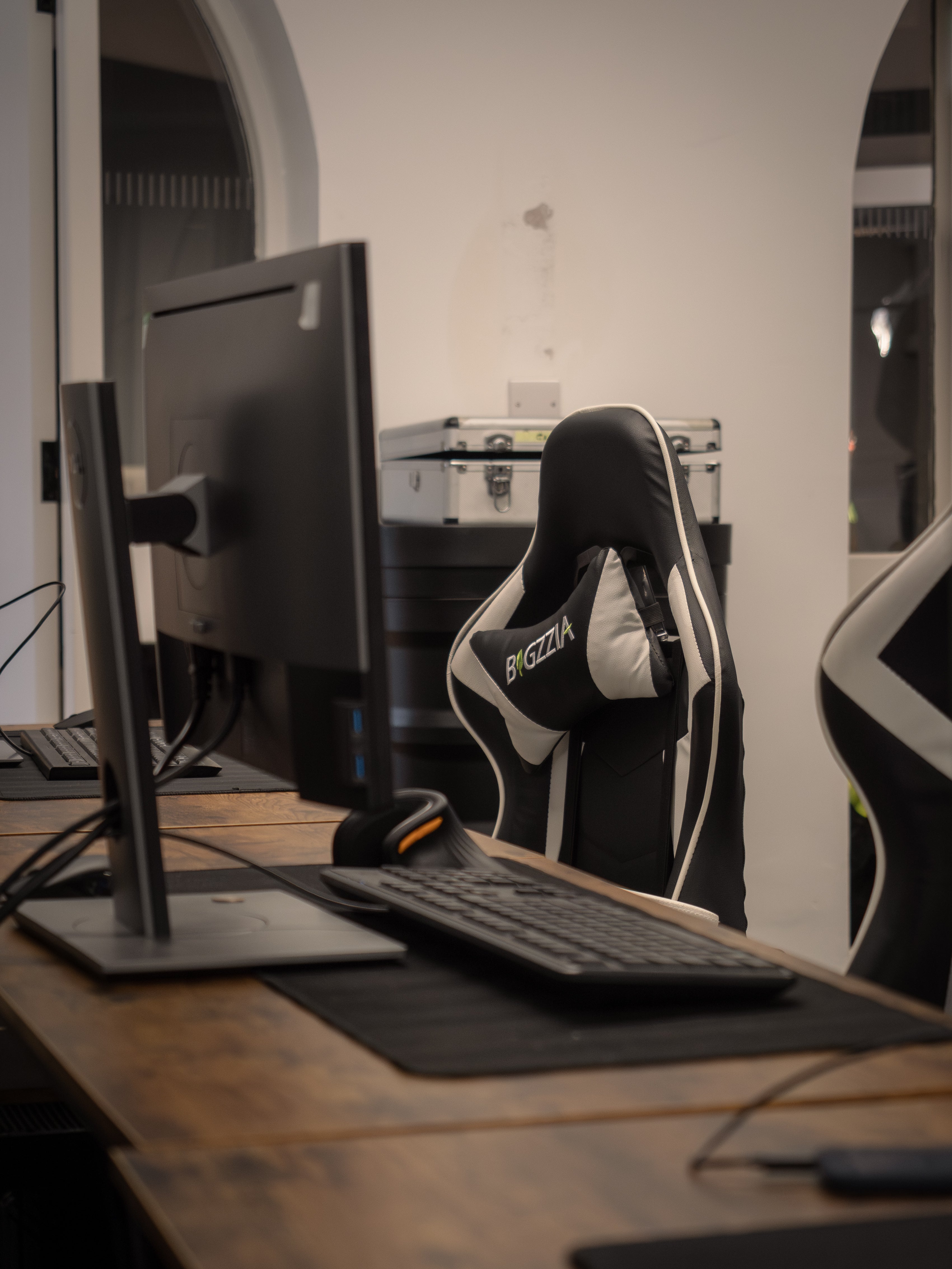 Computer setup with monitor, keyboard, and chair in a room.